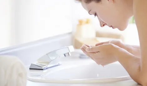 Woman washing her face with water